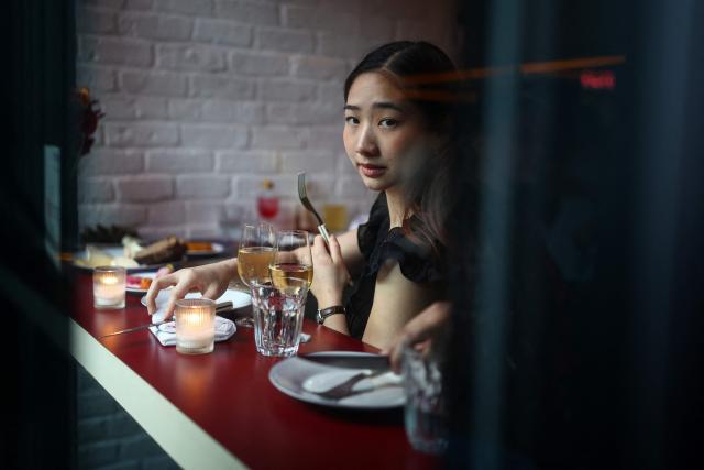 A woman looks on as she has dinner at the French restaurant Gigi’s in the Brooklyn borough of New York on April 26, 2026. Hugo Hivernat's restaurant was only open for a few days before he got dragged into New York City's cost of living row over a portion of half chicken priced at $40. For some on social media, the cost highlights how dining has become prohibitively expensive in the most populous US city. But Hivernat insists his business is barely making a profit. (Photo by CHARLY TRIBALLEAU / AFP)