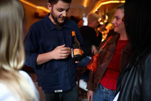 A waiter presents a bottle of wine to customers during dinner in the French restaurant Gigi’s in the Brooklyn borough of New York on April 26, 2026. Hugo Hivernat's restaurant was only open for a few days before he got dragged into New York City's cost of living row over a portion of half chicken priced at $40. For some on social media, the cost highlights how dining has become prohibitively expensive in the most populous US city. But Hivernat insists his business is barely making a profit. (Photo by CHARLY TRIBALLEAU / AFP)