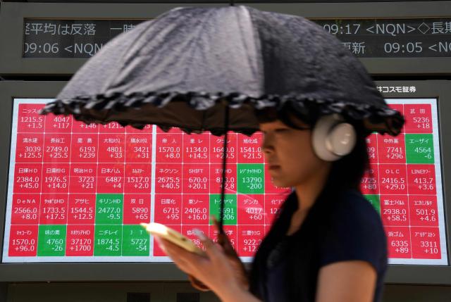A woman walks past an electronic quotation board displaying the Nikkei 225 stock prices on the Tokyo Stock Exchange in Tokyo on April 28, 2026. (Photo by Kazuhiro NOGI / AFP)
