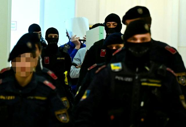 Two defendants in handcuffs are escorted to the courtroom by justice officers as a trial starts at court in Wiener Neustadt, Austria, on April 28, 2026, over a plot to attack a Taylor Swift concert in Vienna. The main suspect, who has been in detention since his arrest in August 2024, is facing terror offenses and other charges, prosecutors said. (Photo by ROLAND SCHLAGER / APA / AFP) / Austria OUT
