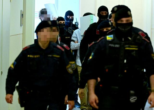 Two defendants in handcuffs are escorted to the courtroom by justice officers as a trial starts at court in Wiener Neustadt, Austria, on April 28, 2026, over a plot to attack a Taylor Swift concert in Vienna. The main suspect, who has been in detention since his arrest in August 2024, is facing terror offenses and other charges, prosecutors said. (Photo by ROLAND SCHLAGER / APA / AFP) / Austria OUT