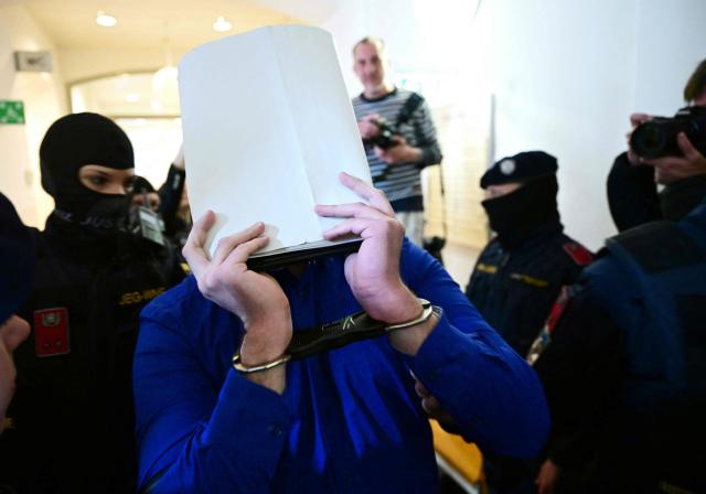 A defendant in handcuffs is escorted to the courtroom by justice officers as a trial starts at court in Wiener Neustadt, Austria, on April 28, 2026, over a plot to attack a Taylor Swift concert in Vienna. The main suspect, who has been in detention since his arrest in August 2024, is facing terror offenses and other charges, prosecutors said. (Photo by ROLAND SCHLAGER / APA / AFP) / Austria OUT