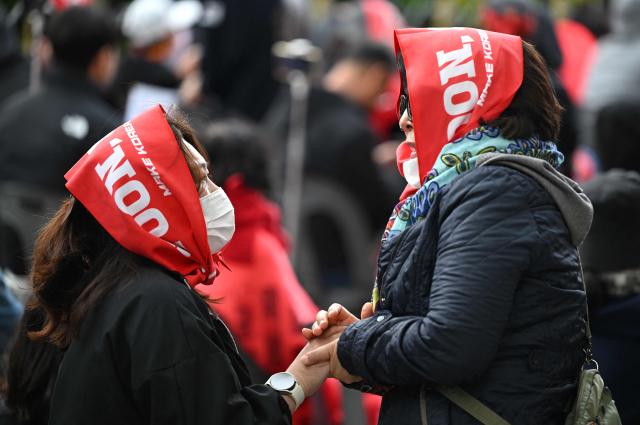 Supporters of South Korea's former president Yoon Suk Yeol and his wife Kim Keon Hee react as they watch a live stream of the trial of the former first lady on a street near the Seoul High Court in Seoul on April 28, 2026. A South Korean appeals court increased the corruption sentence for former first lady Kim Keon Hee on April 28 to four years in jail, up from 20 months, after finding her guilty of stock manipulation and bribery. (Photo by Jung Yeon-je / AFP)