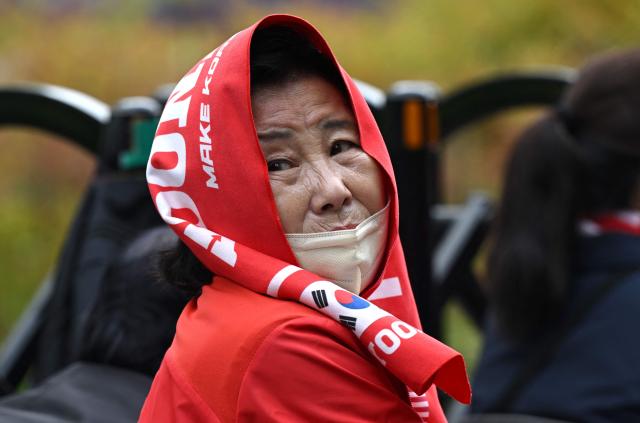 A supporter of South Korea's former president Yoon Suk Yeol and his wife Kim Keon Hee reacts as she watches a live stream of the trial of the former first lady on a street near the Seoul High Court in Seoul on April 28, 2026. A South Korean appeals court increased the corruption sentence for former first lady Kim Keon Hee on April 28 to four years in jail, up from 20 months, after finding her guilty of stock manipulation and bribery. (Photo by Jung Yeon-je / AFP)