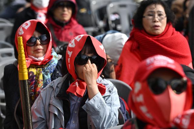 Supporters of South Korea's former president Yoon Suk Yeol and his wife Kim Keon Hee react as they watch a live stream of the trial of the former first lady on a street near the Seoul High Court in Seoul on April 28, 2026. A South Korean appeals court increased the corruption sentence for former first lady Kim Keon Hee on April 28 to four years in jail, up from 20 months, after finding her guilty of stock manipulation and bribery. (Photo by Jung Yeon-je / AFP)