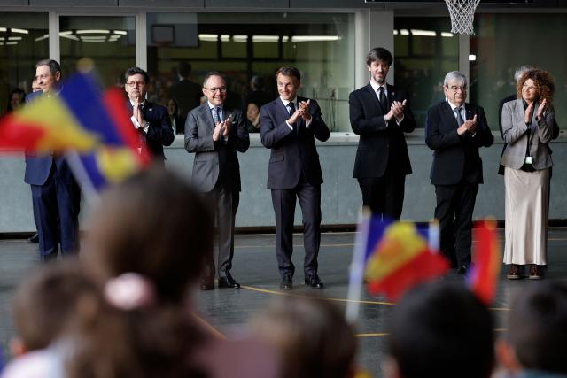 France's President and Co-Prince of Andorra Emmanuel Macron (C) applauds and poses alongside Prefect of the Provence-Alpes-Cote d'Azur region Georges-François Leclerc (2ndL) and Andorra's Prime Minister Xavier Espot Zamora (3rdL) as he meets with students and teachers at a school in Santa Coloma, on the second day of his visit to the microstate of Andorra on April 28, 2026. (Photo by Valentine CHAPUIS / POOL / AFP)