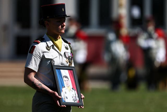A member of the 132e Regiment d'Infanterie Cynotechnique - 132e RIC (132nd Canine Infantry Regiment) holds a portrait of French Army Staff Sergeant Anicet Girardin who died on April 22, 2026 from wounds suffered in a weekend ambush against UN peacekeepers in Lebanon, during a tribute ceremony in Suippes, eastern France on April 28, 2026. Anicet Girardin, who was posthumously promoted to sergeant, is the third French soldier to be killed since the start, on February 28, of the war waged by Israel and the United States against Iran. (Photo by Sameer AL-DOUMY / AFP)