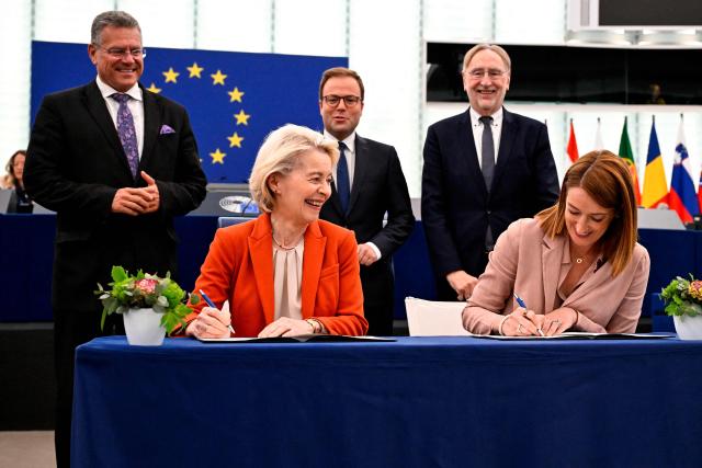 European Commission President Ursula von der Leyen (L) and European Parliament President Roberta Metsola (R) react as they sign a framework agreement governing relations between EP and EC while (background L to R) EU Commissioner for Trade and Economic Security Maros Sefcovic, MEP and rapporteur Sven Simon and MEP Bernd Lange stand behind in the auditorium of the European Parliament in Strasbourg, north eastern France, on April 28, 2026. (Photo by Jean-Christophe VERHAEGEN / AFP)
