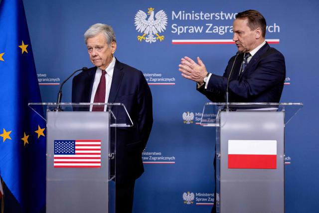 Polish Foreign Minister Radoslaw Sikorski (R) applauds for the US President's Special Envoy for Belarus John Cole as they address a press conference at the ministry building in Warsaw on April 28, 2026, after an exchange of prisoners. Poland on April 28 released a jailed Russian archaeologist, who was wanted by Ukraine, as part of a multi-country swap deal that also saw a Polish journalist freed from a Belarusian jail. (Photo by Wojtek RADWANSKI / AFP)