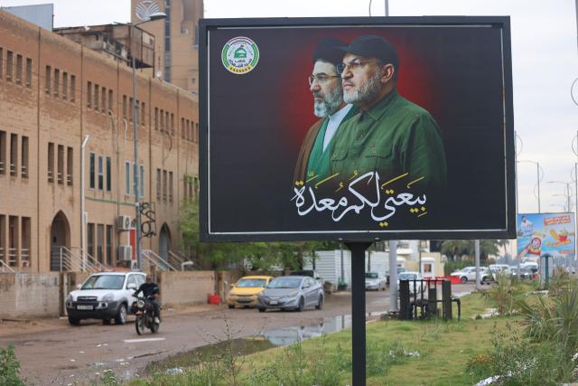 A motorcyclist rides past a poster showing Abu Ala al-Walai (R) and Iranian Supreme Leader Mojtaba Khamenei (L) in Baghdad on April 28, 2026. The US State Department has offered a reward of up to $10 million for information leading to the capture of Hashim Finyan Rahimi al-Saraji, the secretary-general of the Iranian-backed Iraqi militia Kataib Sayyid al-Shuhada, which Washington considers a terrorist organisation. The State Department said in a social media post on April 23 that the search is underway for al-Saraji, also known as Abu Ala al-Walai. (Photo by AHMAD AL-RUBAYE / AFP)