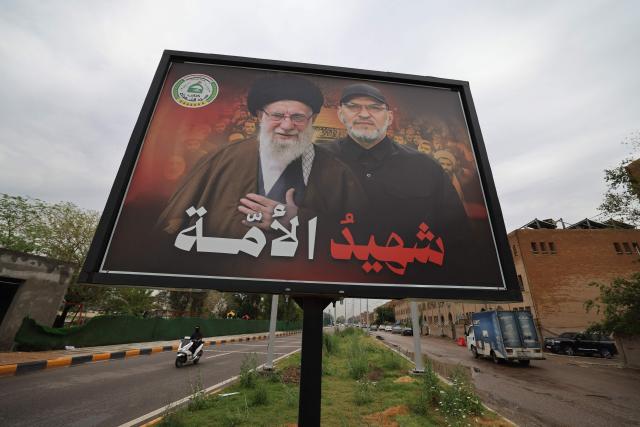 A motorcyclist rides past a poster showing Abu Ala al-Walai (R) and the late Iranian Supreme Leader Ayatollah Ali Khamenei (L) in Baghdad on April 28, 2026. The US State Department has offered a reward of up to $10 million for information leading to the capture of Hashim Finyan Rahimi al-Saraji, the secretary-general of the Iranian-backed Iraqi militia Kataib Sayyid al-Shuhada, which Washington considers a terrorist organisation. The State Department said in a social media post on April 23 that the search is underway for al-Saraji, also known as Abu Ala al-Walai. (Photo by AHMAD AL-RUBAYE / AFP)