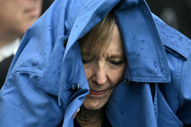 An attendee protects herself from the rain while waiting for US President Donald Trump and First Lady Melania Trump to greet Britain's King Charles III and Queen Camilla for an arrival ceremony on the South Lawn of the White House in Washington, DC, on April 28, 2026. (Photo by Jim WATSON / AFP)