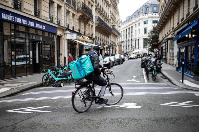 (FILES) A takeaway delivery driver rides a bike in Paris on March 13, 2024, two days after EU states endorsed controversial rules to cover app workers in the so-called gig economy, after weeks of wrangling over the watered-down text. Platform workers must be treated as employees, French left-wing MPs demanded on April 28, 2026. They are set to table a bill, with France having just a few months left to transpose a European directive to this effect into national law. For several years now, the self-employed status of platform workers has been strongly contested by trade unions, NGOs and some politicians, who believe it amounts to disguised employment. (Photo by Guillaume BAPTISTE / AFP)