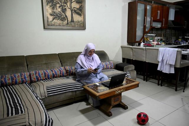 This photograph taken on April 7, 2026 shows Saniya Jafri, a doctor and telemedicine practitioner with the digital health firm Sehat Kahani, conducting online patient consultations at her residence in Karachi. Gallup surveys and doctors' associations suggest more than a third of Pakistani female medical graduates never enter the profession -- or leave it after marriage -- due to lack of family support, poor childcare facilities, and harassment. But an initiative by digital health firm Sehat Kahani helped women back into the workforce by providing a digital platform to connect home-based, mostly female doctors, with patients in underserved communities. (Photo by Rizwan TABASSUM / AFP)