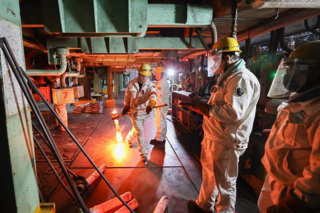 A worker carries a red hot steel bar in a steel casting workshop in Lianyungang, in China’s eastern Jiangsu province on April 28, 2026. (Photo by CN-STR / AFP) / China OUT