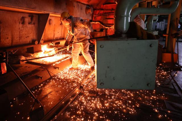 TOPSHOT - A worker moves a red hot steel bar in a steel casting workshop in Lianyungang, in China’s eastern Jiangsu province on April 28, 2026. (Photo by CN-STR / AFP) / China OUT