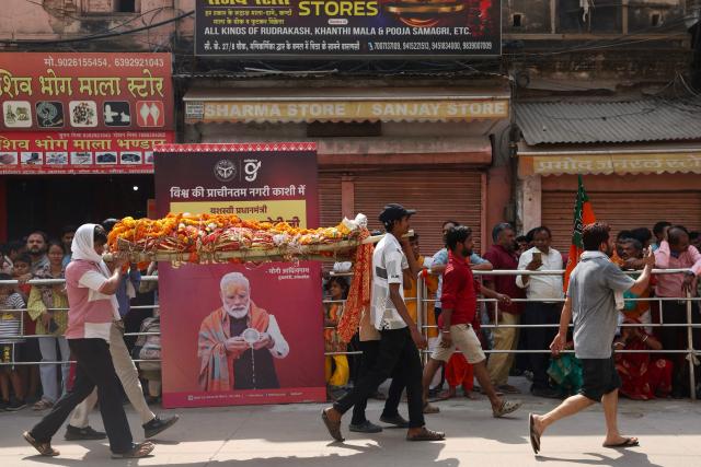 Relatives carry the deceased for funeral rites as people wait along a road during Indian Prime Minister Narendra Modi's visit in Varanasi on April 29, 2026. (Photo by Niharika KULKARNI / AFP)