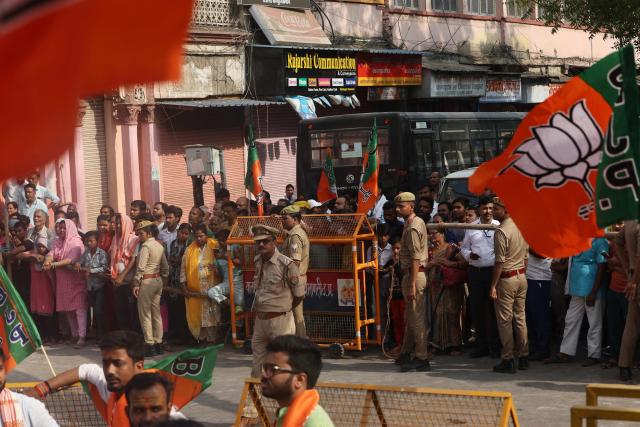Police personnel stand guard as supporters wait along a road during Indian Prime Minister Narendra Modi's visit in Varanasi on April 29, 2026. (Photo by Niharika KULKARNI / AFP)