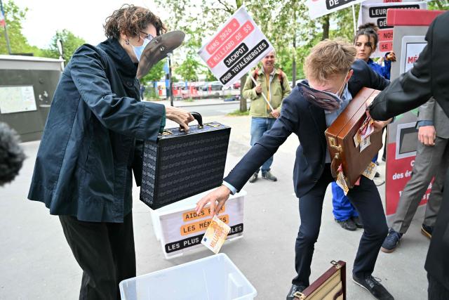 Protesters collects fake notes during a staged protest action called by 350.org, Action Justice Climat, Attac France, Greenpeace France and Extinction Rebellion France against French company TotalEnergies marking the publication of its first-quarter results in Paris on April 29, 2026. French oil and gas giant TotalEnergies reported on April 29, 2026, a first-quarter net profit of $5.8 billion, up by nearly 50% year-on-year, driven by rising oil prices linked to the war in the Middle East. (Photo by Martin LELIEVRE / AFP)