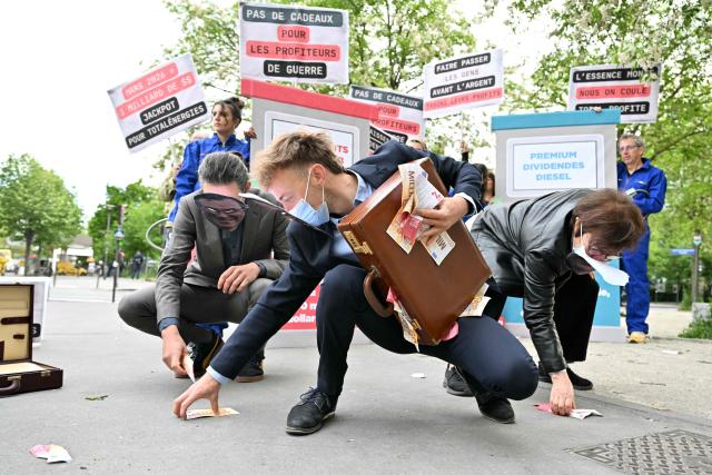 Protesters collects fake notes during a staged protest action called by 350.org, Action Justice Climat, Attac France, Greenpeace France and Extinction Rebellion France against French company TotalEnergies marking the publication of its first-quarter results in Paris on April 29, 2026. French oil and gas giant TotalEnergies reported on April 29, 2026, a first-quarter net profit of $5.8 billion, up by nearly 50% year-on-year, driven by rising oil prices linked to the war in the Middle East. (Photo by Martin LELIEVRE / AFP)