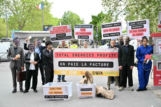 Protesters, some wearing masks bearing TotalEnergies CEO Patrick  Pouyanne and Economy, Finances and Industry Minister Roland Lescure, take part in a staged protest action called by 350.org, Action Justice Climat, Attac France, Greenpeace France and Extinction Rebellion France against French company TotalEnergies marking the publication of its first-quarter results in Paris on April 29, 2026. French oil and gas giant TotalEnergies reported on April 29, 2026, a first-quarter net profit of $5.8 billion, up by nearly 50% year-on-year, driven by rising oil prices linked to the war in the Middle East. (Photo by Martin LELIEVRE / AFP)