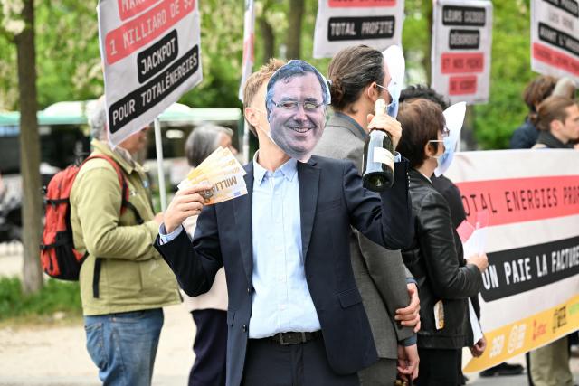 A protester wears a mask bearing Patrick Pouyanne, Chairman and CEO of TotalEnergies, during a staged protest action called by 350.org, Action Justice Climat, Attac France, Greenpeace France and Extinction Rebellion France against French company TotalEnergies marking the publication of its first-quarter results in Paris on April 29, 2026. French oil and gas giant TotalEnergies reported on April 29, 2026, a first-quarter net profit of $5.8 billion, up by nearly 50% year-on-year, driven by rising oil prices linked to the war in the Middle East. (Photo by Martin LELIEVRE / AFP)