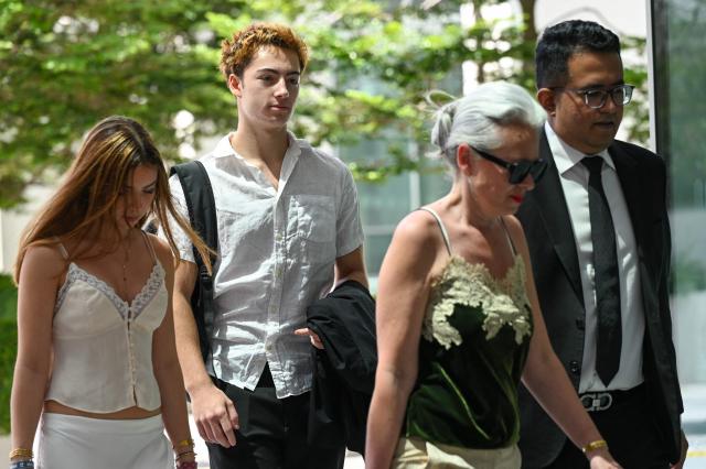 French teenager Didier Gaspard Owen Maximilien (2nd L) arrives for an application to leave jurisdiction, for the court's permission to leave Singapore, at the State Courts in Singapore on April 29, 2026. A French teenager has been charged with mischief and public nuisance in Singapore for licking a straw and putting it back in an orange juice vending machine, court documents showed April 27. (Photo by Roslan RAHMAN / AFP)