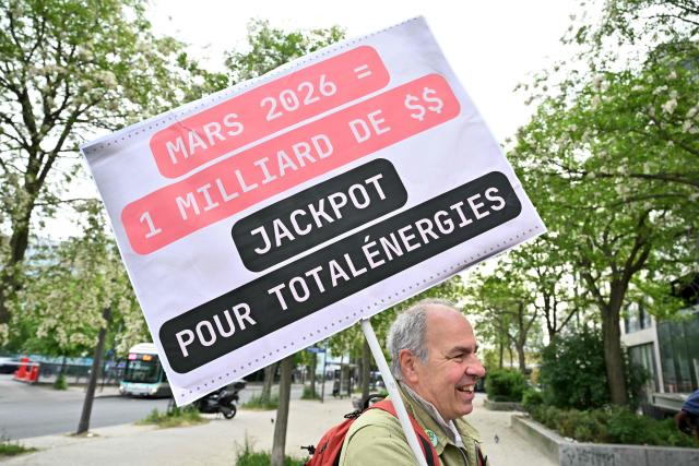 A protester holds a placard during a staged protest action called by 350.org, Action Justice Climat, Attac France, Greenpeace France and Extinction Rebellion France against French company TotalEnergies marking the publication of its first-quarter results in Paris on April 29, 2026. French oil and gas giant TotalEnergies reported on April 29, 2026, a first-quarter net profit of $5.8 billion, up by nearly 50% year-on-year, driven by rising oil prices linked to the war in the Middle East. (Photo by Martin LELIEVRE / AFP)