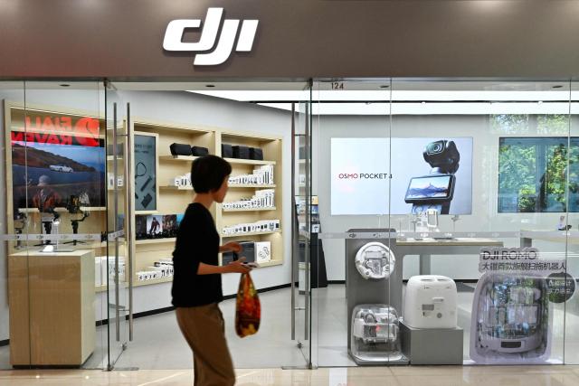 A person walks past a DJI store at a mall in Beijing on April 29, 2026, ahead a ban against the sale of consumer drones by the city government which begins on May 1. (Photo by Adek BERRY / AFP)