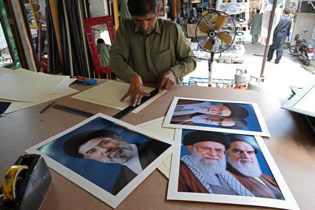 An artisan prepares portraits of Iran’s newly elected supreme leader Mojtaba Khamenei (L), alongside slain leaders Ayatollah Ruhollah Khomeini (R) and Ayatollah Ali Khamenei (C) at a market in Islamabad on April 29, 2026. (Photo by Aamir QURESHI / AFP)