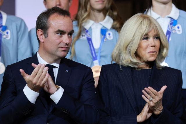 France's Prime Minister Sebastien Lecornu and wife of France's President Brigitte Macron applaud as they pose for a group photo during a medal ceremony in honour of French athletes who competed in the Milan-Cortina 2026 Winter Olympic Games at the Elysee presidential Palace in Paris, on April 29, 2026. (Photo by Stephanie Lecocq / POOL / AFP)