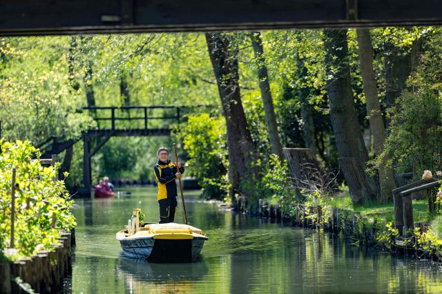 Deutsche Post delivery staff member Andrea Bunar manoeuvers her vessel as she makes the season opening delivery tour of the Spreewald barge postal delivery service on April 29, 2026. Mail delivery by barge has a 129-year-old tradition in the Spreewald region. Every week, more than 600 letters, registered mail and postcards as well as around 80 parcels are delivered across the river, as many of the 65 households in Lehde do not have a direct road connection, according to German postal service Deutsche Post. (Photo by Odd ANDERSEN / AFP)