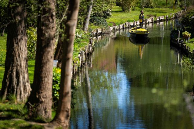 Deutsche Post delivery staff member Andrea Bunar manoeuvers her vessel as she makes the season opening delivery tour of the Spreewald barge postal delivery service on April 29, 2026. Mail delivery by barge has a 129-year-old tradition in the Spreewald region. Every week, more than 600 letters, registered mail and postcards as well as around 80 parcels are delivered across the river, as many of the 65 households in Lehde do not have a direct road connection, according to German postal service Deutsche Post. (Photo by Odd ANDERSEN / AFP)