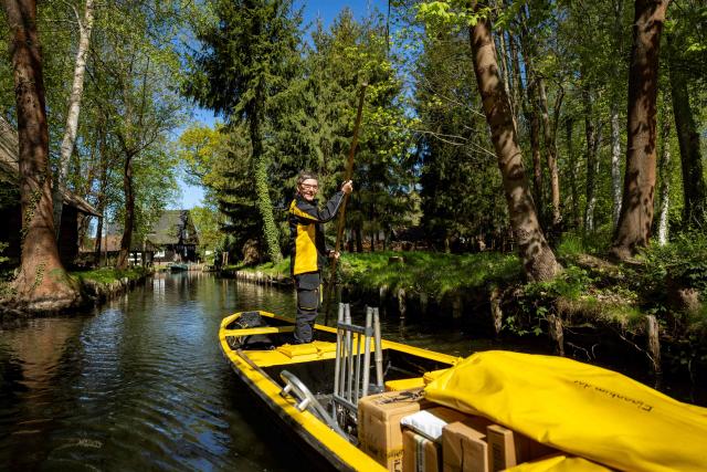 Deutsche Post delivery staff member Andrea Bunar manoeuvers her vessel as she makes the season opening delivery tour of the Spreewald barge postal delivery service on April 29, 2026. Mail delivery by barge has a 129-year-old tradition in the Spreewald region. Every week, more than 600 letters, registered mail and postcards as well as around 80 parcels are delivered across the river, as many of the 65 households in Lehde do not have a direct road connection, according to German postal service Deutsche Post. (Photo by Odd ANDERSEN / AFP)
