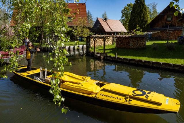 Deutsche Post delivery staff member Andrea Bunar manoeuvers her vessel as she makes the season opening delivery tour of the Spreewald barge postal delivery service on April 29, 2026. Mail delivery by barge has a 129-year-old tradition in the Spreewald region. Every week, more than 600 letters, registered mail and postcards as well as around 80 parcels are delivered across the river, as many of the 65 households in Lehde do not have a direct road connection, according to German postal service Deutsche Post. (Photo by Odd ANDERSEN / AFP)