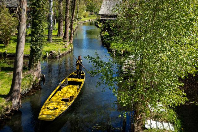 Deutsche Post delivery staff member Andrea Bunar manoeuvers her vessel as she makes the season opening delivery tour of the Spreewald barge postal delivery service on April 29, 2026. Mail delivery by barge has a 129-year-old tradition in the Spreewald region. Every week, more than 600 letters, registered mail and postcards as well as around 80 parcels are delivered across the river, as many of the 65 households in Lehde do not have a direct road connection, according to German postal service Deutsche Post. (Photo by Odd ANDERSEN / AFP)