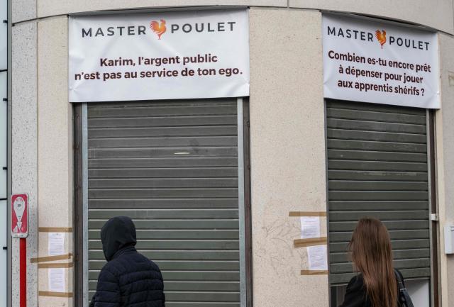 Pedestrians walk past a Master Poulet, a fast food restaurant  specialised in low-cost halal grilled chicken, in Saint-Ouen, a northern suburb of Paris on April 29, 2026. In Saint-Ouen (Seine-Saint-Denis), a showdown is pitting the halal fast-food chain Master Poulet against the Socialist mayor Karim Bouamrane, amid mutual accusations of gentrifying the city and promoting "junk food". (Photo by Martin LELIEVRE / AFP)