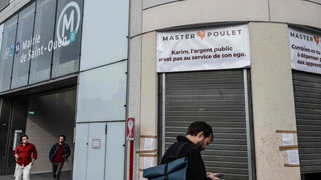 Pedestrians walk past a Master Poulet, a fast food restaurant  specialised in low-cost halal grilled chicken, in Saint-Ouen, a northern suburb of Paris on April 29, 2026. In Saint-Ouen (Seine-Saint-Denis), a showdown is pitting the halal fast-food chain Master Poulet against the Socialist mayor Karim Bouamrane, amid mutual accusations of gentrifying the city and promoting "junk food". (Photo by Martin LELIEVRE / AFP)