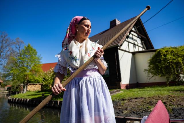 A woman wearing a traditional Sorb outfit manouvers a so-called "Spreewaldkahn" barge carrying tourists along a canal in the Spreewald region in Luebbenau, eastern Germany, on April 29, 2026. (Photo by Odd ANDERSEN / AFP)