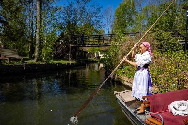A woman wearing a traditional Sorb outfit manouvers a so-called "Spreewaldkahn" barge used to carry tourists along a canal in the Spreewald region in Luebbenau, eastern Germany, on April 29, 2026. (Photo by Odd ANDERSEN / AFP)