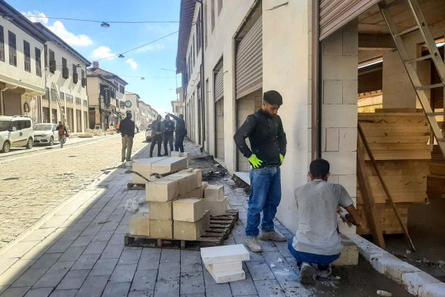 Two employees work on the reconstruction of a building on Kurtulus Street, located in the old town of Antakya, on March 31, 2026, over three years after the earthquake that devastated southeastern Turkey, including Antakya, on February 6, 2023. Nothing is "as it was before" the earthquake that devastated the ancient city and southern Turkey in February 2023, killing at least 53,000 people : Three years after the disaster, residents are denouncing opaque reconstruction plans that threaten to empty the old town and jeopardise its multicultural identity. Once bustling, adjacent to working-class neighbourhoods as well as Muslim, Christian and Jewish places of worship, Kurtulus Avenue is now a vast construction site where listed historic buildings are being hastily rebuilt, with support from the European Union. The old town of Antakya was home to more than 13,000 residents before the earthquake, but virtually no homes will remain, according to the controversial new urban development plan. (Photo by Burcin GERCEK / AFP) / TO GO WITH AFP STORY BY BURC?N GERCEK