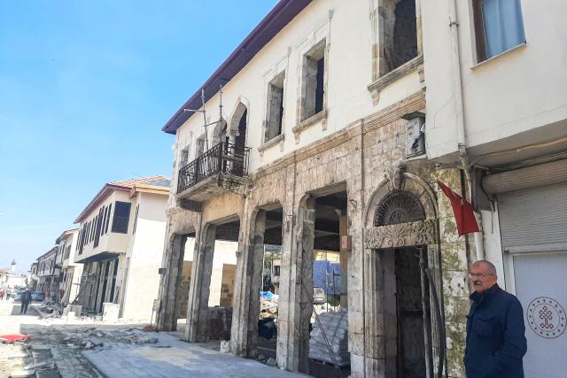 Local resident Kemal Aribas stands in front of historical coffee shop "Affan Coffee" undergoing renovation, located in the old town of Antakya on April 1, 2026, over three years after the earthquake that devastated southeastern Turkey, including Antakya, on February 6, 2023. Nothing is "as it was before" the earthquake that devastated the ancient city and southern Turkey in February 2023, killing at least 53,000 people : Three years after the disaster, residents are denouncing opaque reconstruction plans that threaten to empty the old town and jeopardise its multicultural identity. Once bustling, adjacent to working-class neighbourhoods as well as Muslim, Christian and Jewish places of worship, Kurtulus Avenue is now a vast construction site where listed historic buildings are being hastily rebuilt, with support from the European Union. The old town of Antakya was home to more than 13,000 residents before the earthquake, but virtually no homes will remain, according to the controversial new urban development plan. (Photo by Burcin GERCEK / AFP) / TO GO WITH AFP STORY BY BURC?N GERCEK