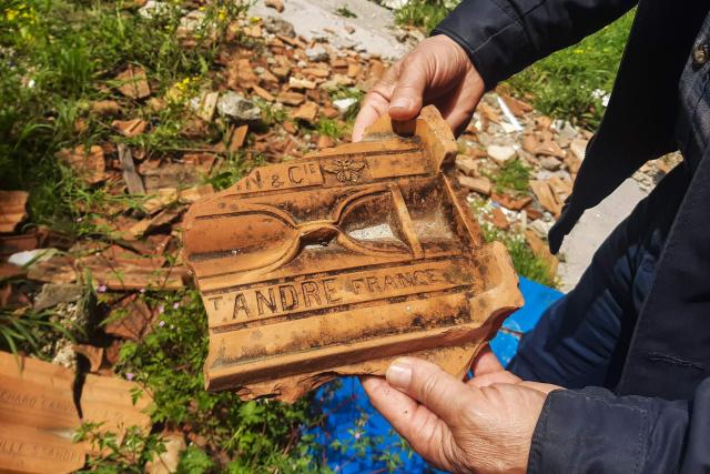 Local resident Kemal Aribas holds the debris of a tile built in Marseille, southeastern France, at a school in the old town heavily of Antakya on April 1, 2026, over three years after the earthquake that devastated southeastern Turkey, including Antakya, on February 6, 2023. Nothing is "as it was before" the earthquake that devastated the ancient city and southern Turkey in February 2023, killing at least 53,000 people : Three years after the disaster, residents are denouncing opaque reconstruction plans that threaten to empty the old town and jeopardise its multicultural identity. Once bustling, adjacent to working-class neighbourhoods as well as Muslim, Christian and Jewish places of worship, Kurtulus Avenue is now a vast construction site where listed historic buildings are being hastily rebuilt, with support from the European Union. The old town of Antakya was home to more than 13,000 residents before the earthquake, but virtually no homes will remain, according to the controversial new urban development plan. (Photo by Burcin GERCEK / AFP) / TO GO WITH AFP STORY BY BURC?N GERCEK