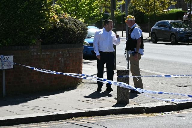 A person talks to a security officer at a cordon in the Golders Green neighbourhood of north London, on April 29, 2026. Two people were stabbed on April 29 following a series of arson attacks targeting Jewish sites in the area. A man was arrested after he was seen running with a knife "attempting to stab Jewish members of the public", the Shomrim Jewish neighbourhood watch said on social media. (Photo by JUSTIN TALLIS / AFP)