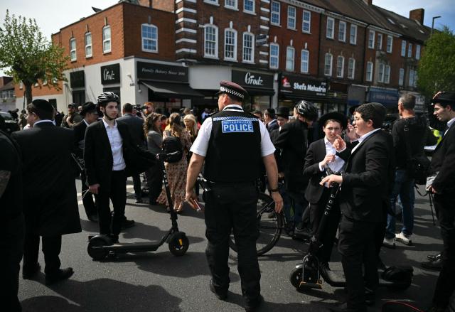 A Metropolitan Police officers asks younger members of the Jewish community to move away from a cordon at the junction of Golders Green Road and Beverley Gardens, in the Golders Green neighbourhood of north London, on April 29, 2026, after two people were stabbed, and a suspect arrested. Two people were stabbed Wednesday in north London, Jewish groups said, following a series of arson attacks targeting Jewish sites in the area, as UK Prime Minister Keir Starmer called the incident "deeply concerning". A man was arrested after he was seen running with a knife "attempting to stab Jewish members of the public", the Shomrim Jewish neighbourhood watch said on social media. (Photo by JUSTIN TALLIS / AFP)