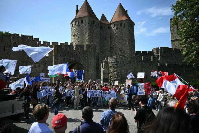 Protesters wave flags as they demonstrate in front of the medieval citadel at the call of "Nous Carcassonne" collective against the decisions taken by Carcassonne's 'Rassemblement National' newly elected mayor, in Carcassonne, southwestern France on April 29, 2026. (Photo by LIONEL BONAVENTURE / AFP)