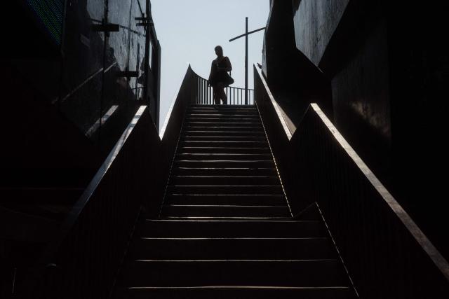 A woman walks down a set of stairs from a footbridge in Bangkok on April 29, 2026. (Photo by ANTHONY WALLACE / AFP)