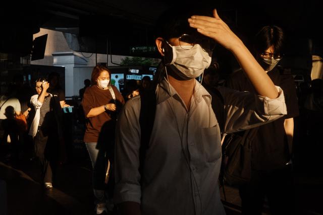 A man shields his face from the sunlight as he leaves a BTS train station in Bangkok on April 29, 2026. (Photo by ANTHONY WALLACE / AFP)
