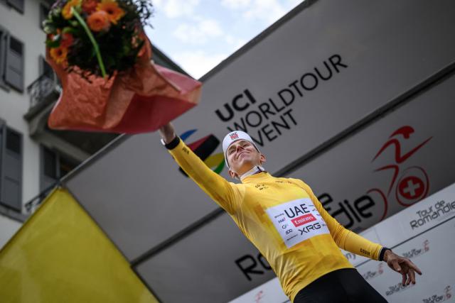 UAE Team Emirates-XRG's Slovenian rider Tadej Pogacar wearing the overall leader's yellow jersey throws flowers during the podium ceremony of the first stage of the Tour of Romandie UCI cycling World tour, a 171.2 km loop from Martigny-Ville to Martigny-Ville, in Martigny, on April 29, 2026. (Photo by Fabrice COFFRINI / AFP)