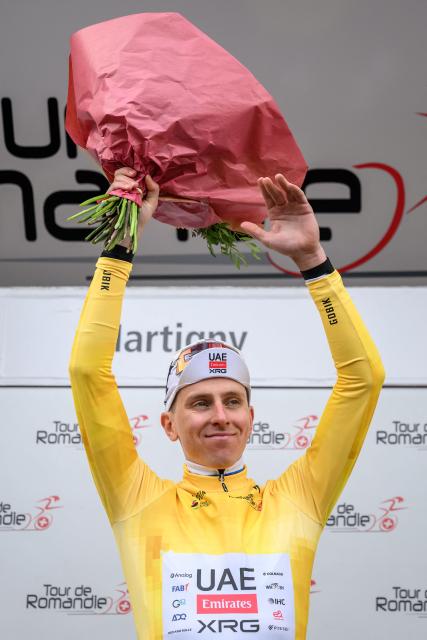 UAE Team Emirates-XRG's Slovenian rider Tadej Pogacar wearing the overall leader's yellow jersey celebrates on the podium of the first stage of the Tour of Romandie UCI cycling World tour, a 171.2 km loop from Martigny-Ville to Martigny-Ville, in Martigny, on April 29, 2026. (Photo by Fabrice COFFRINI / AFP)